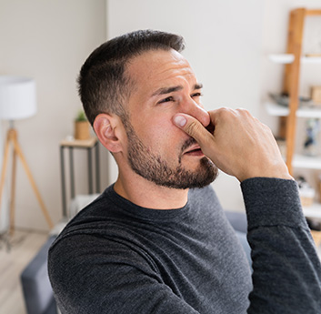 A man holding his nose to avoid the musty smell